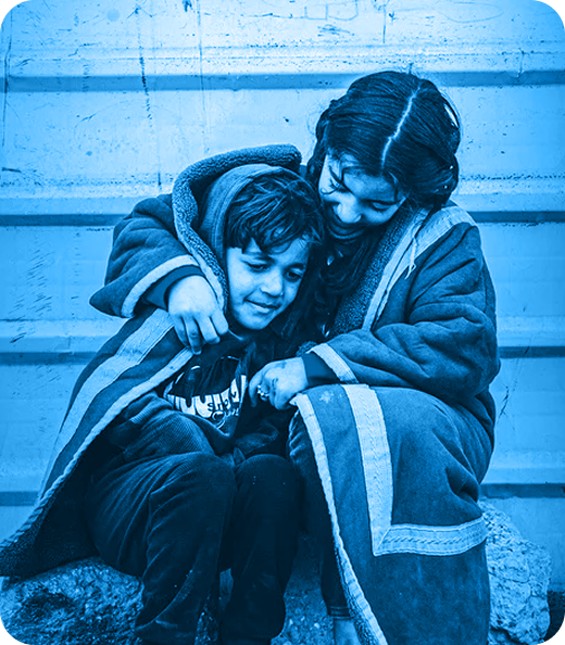 Dos niños sentados juntos y envueltos en mantas, con tono azul.