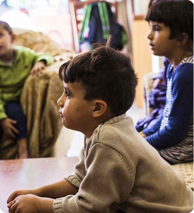 Tres niños sentados en un espacio interior, mirando hacia un lado.